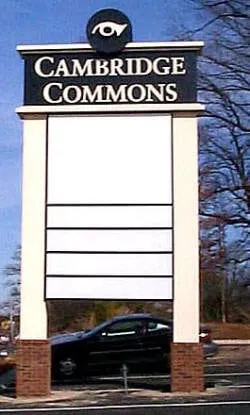 Cambridge Commons pylon sign with empty tenant panels beside a parking lot